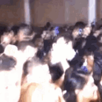 a crowd of people are gathered in a room and dancing .