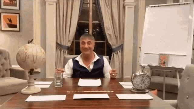 a man is sitting at a table with a glass of water and a pocket watch .