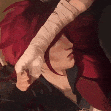 a close up of a person with red hair and bandaged hands .