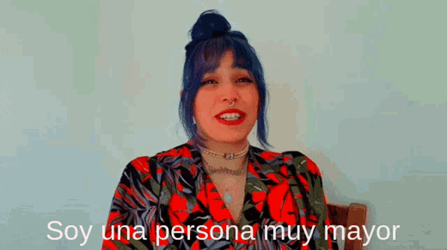 a woman with blue hair is sitting in a chair with the words soy una persona muy mayor above her