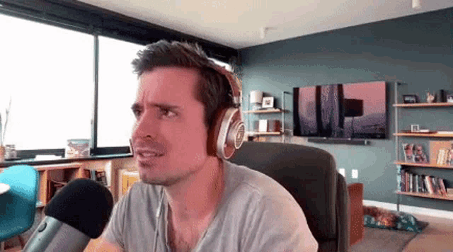 a man wearing headphones and a microphone in a living room .