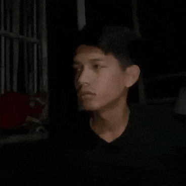 a young man in a black jacket is making a funny face in the dark