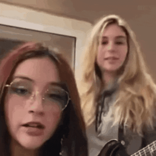 two young women are standing next to each other playing guitars .