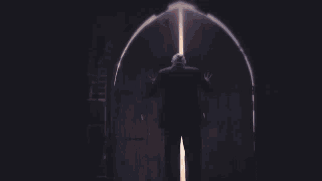 a man in a suit opens a door to a bright light