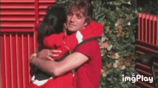 a man and a woman are hugging each other in front of a red building .