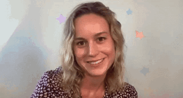 a woman with blonde hair is smiling and looking at the camera while wearing a floral shirt .