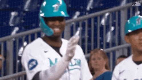 a baseball player wearing a blue helmet and gloves is standing in the stands .