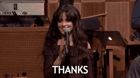 a woman is singing into a microphone and the word thanks is on the bottom of the picture .