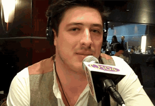 a man wearing headphones is talking into a microphone that says 105.4 on it
