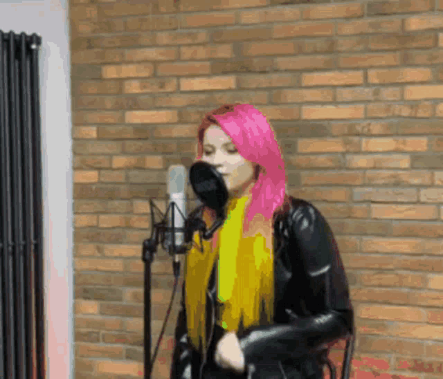 a girl with pink hair singing into a rode microphone