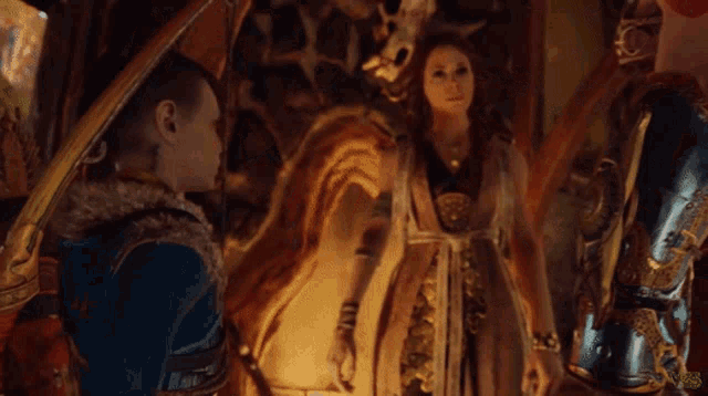 a woman in a gold dress is standing next to a man in a blue vest