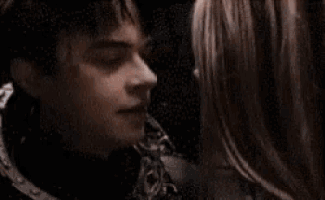 a man and a woman are kissing in a dark room
