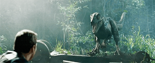 a man is standing next to a dinosaur in the jungle .