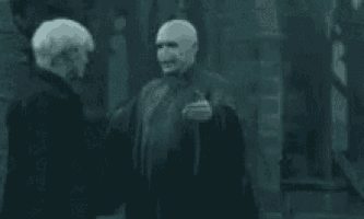 a man in a black robe is hugging another man in a dark room .