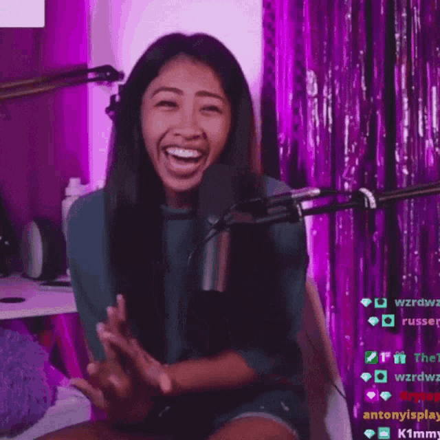 a woman sitting in front of a microphone with a purple curtain behind her that says antonyisplay