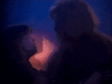 a man and a woman are looking at each other in a dark room