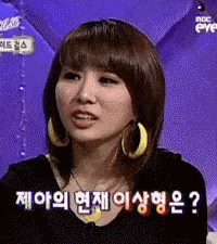 a woman wearing hoop earrings and a black shirt is making a face .