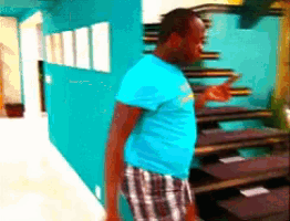 a man in a blue shirt and plaid shorts is standing in front of stairs