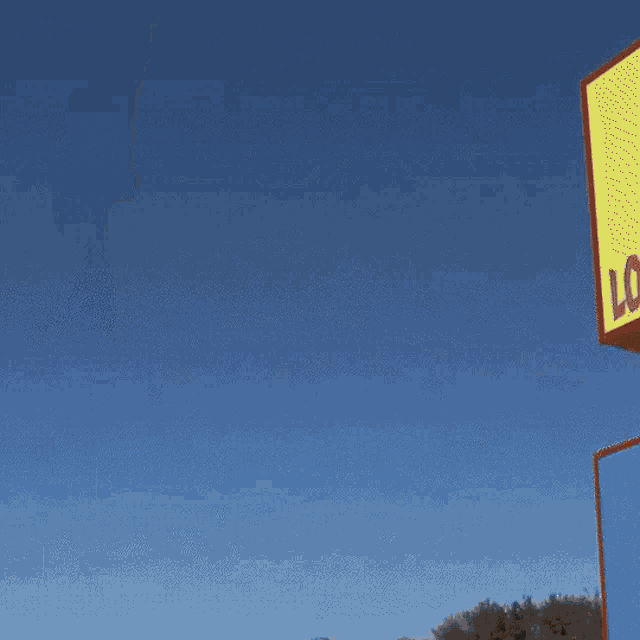 a man in a white shirt and black tie smiles in front of a yellow sign that says lo
