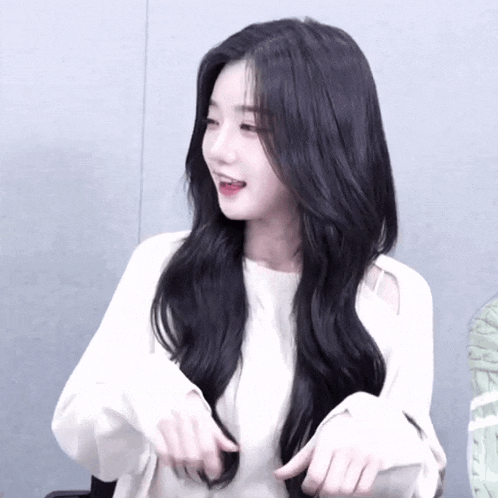 a woman with long black hair is wearing a white top