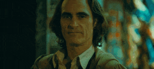 a close up of a man in a suit and tie looking at the camera in a dark room .