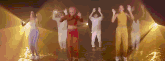 a group of people are standing in a line with their hands in the air .