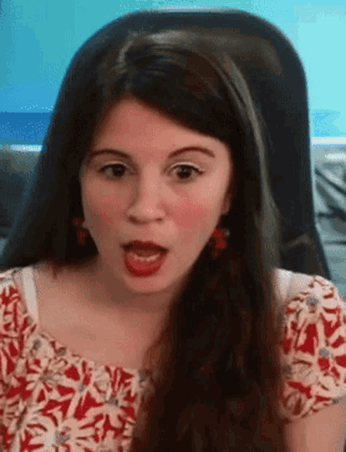 a woman in a red white and blue shirt is sitting in a chair with her mouth open