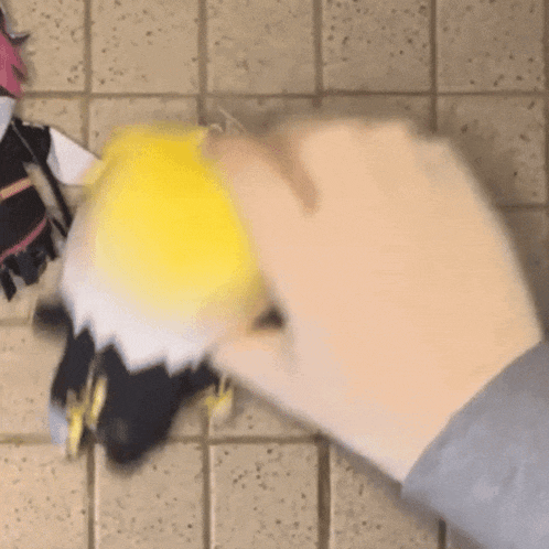 a person is holding a stuffed animal on a tile floor .