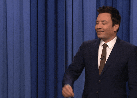 a man in a suit and tie says " rats " in front of a blue curtain