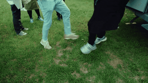 a group of people standing in the grass with their feet visible