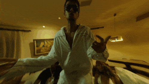 a man wearing sunglasses and a white shirt stands in front of stairs