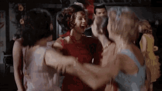 a group of women are dancing together in a circle in a room .