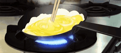 a person is cooking eggs in a frying pan on a stove with chopsticks .