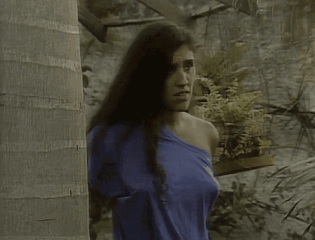 a woman with long hair is wearing a blue off the shoulder shirt