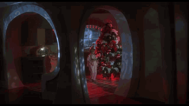 a little girl is standing in a room with a christmas tree in the background