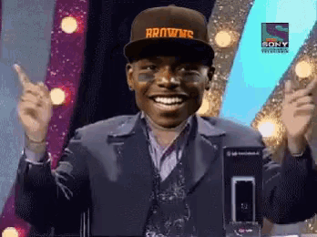 a man wearing a hat that says browns is smiling and pointing