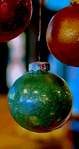 a green christmas ornament is hanging from a string with other ornaments