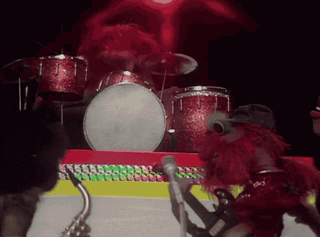 a muppet playing drums and a muppet playing a saxophone on a stage