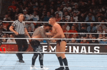 two men in a wrestling ring with a sign that says em finals in the background
