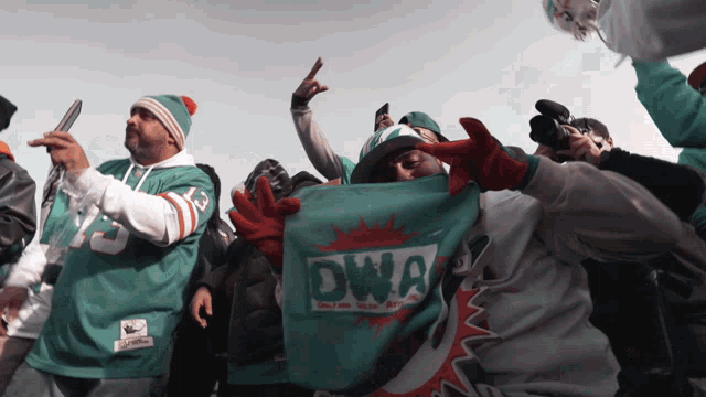 a man in a miami dolphins jersey holds up a flag that says dwa