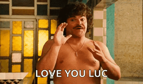 a shirtless man with a mustache is standing in front of a window and says `` love you luc '' .