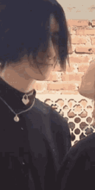a man with long black hair and a necklace is standing next to a woman in a black shirt .