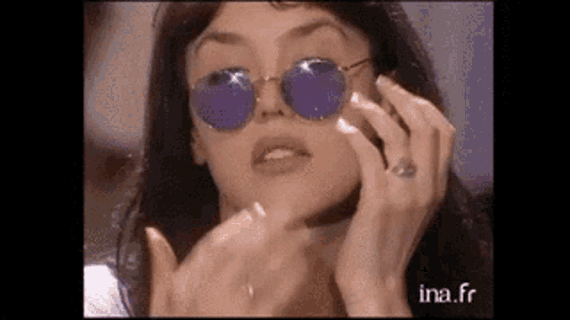 a woman wearing sunglasses and a ring is talking on a phone .