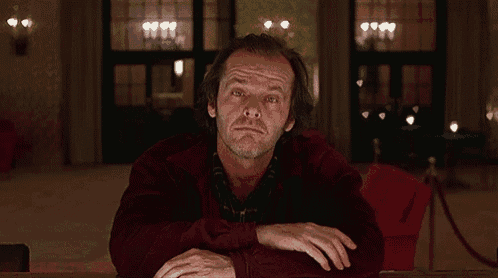 a man in a red sweater is sitting at a table with his mouth wide open .