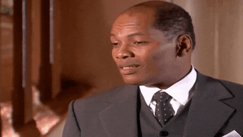 a man in a suit and tie looks to his left