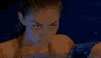 three women are swimming in a pool with blue lights behind them .