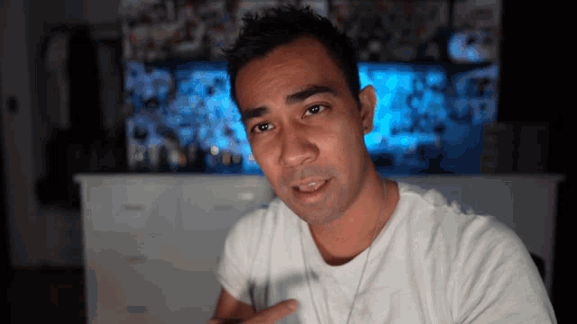 a man in a white t-shirt is pointing to his chest