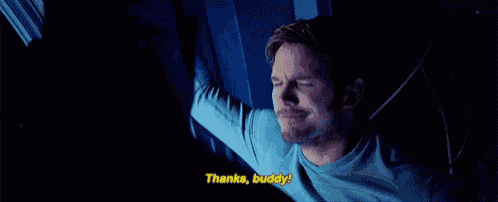 a man in a blue shirt is standing in front of a computer screen and says `` thanks , buddy '' .