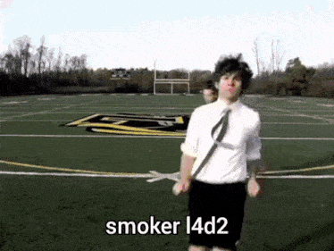 a man in a white shirt and tie is standing on a football field with the words smoker 14d2 written on the bottom