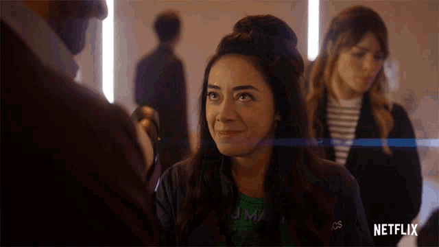 a woman wearing a green shirt that says ' jma ' on it smiles in front of a netflix logo
